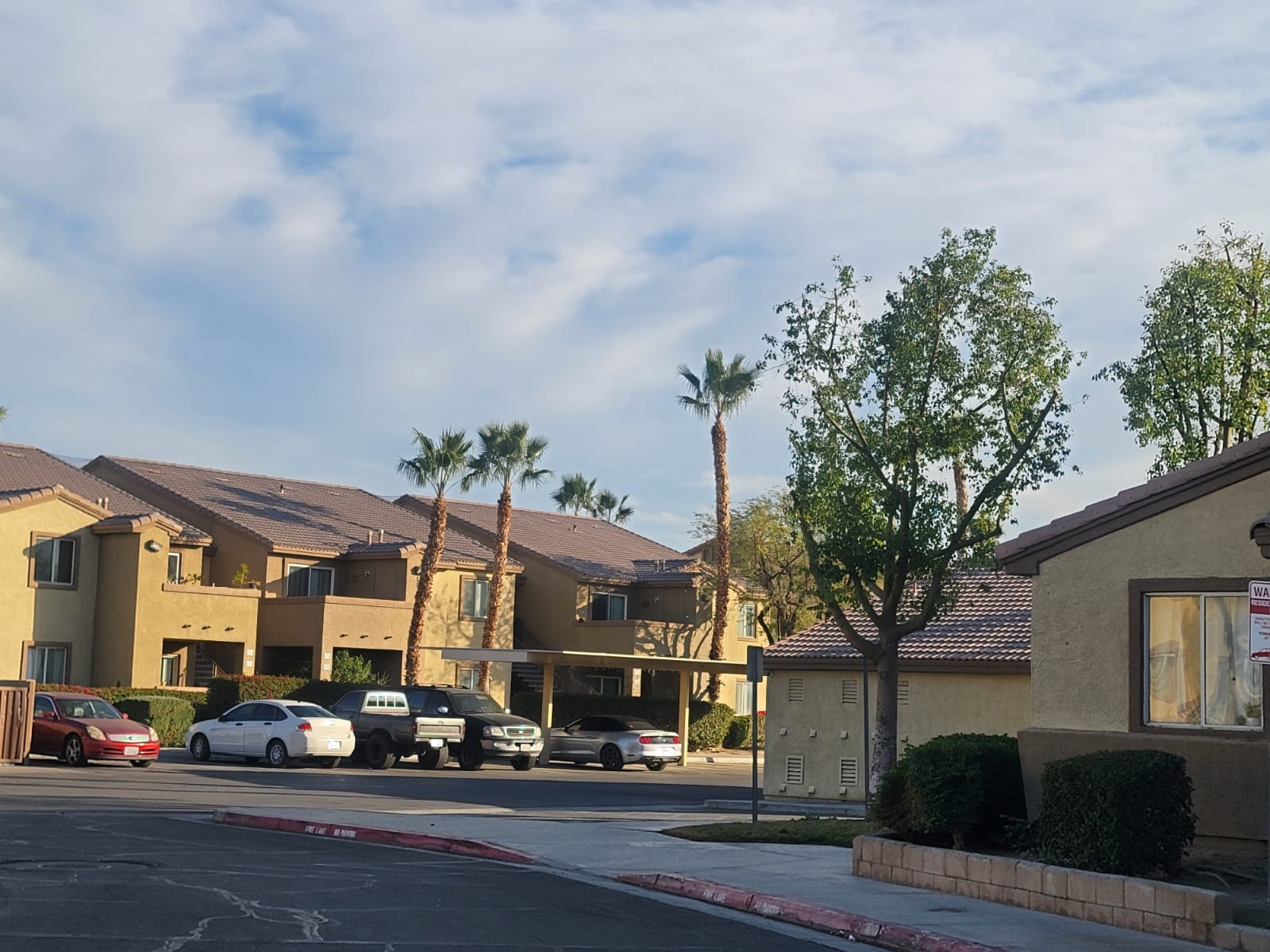 A row of houses with cars parked in front.